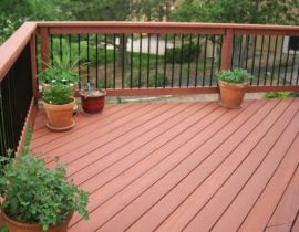 A redwood deck with the boards at 45-degrees to the joists. The railing has wood components and drink cap with round metal balusters.