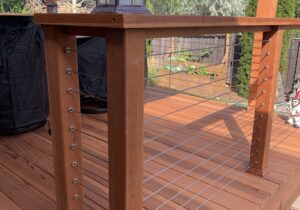 Custom designed and built railing that incorporates wood components and drink cap with stainless steel cables.