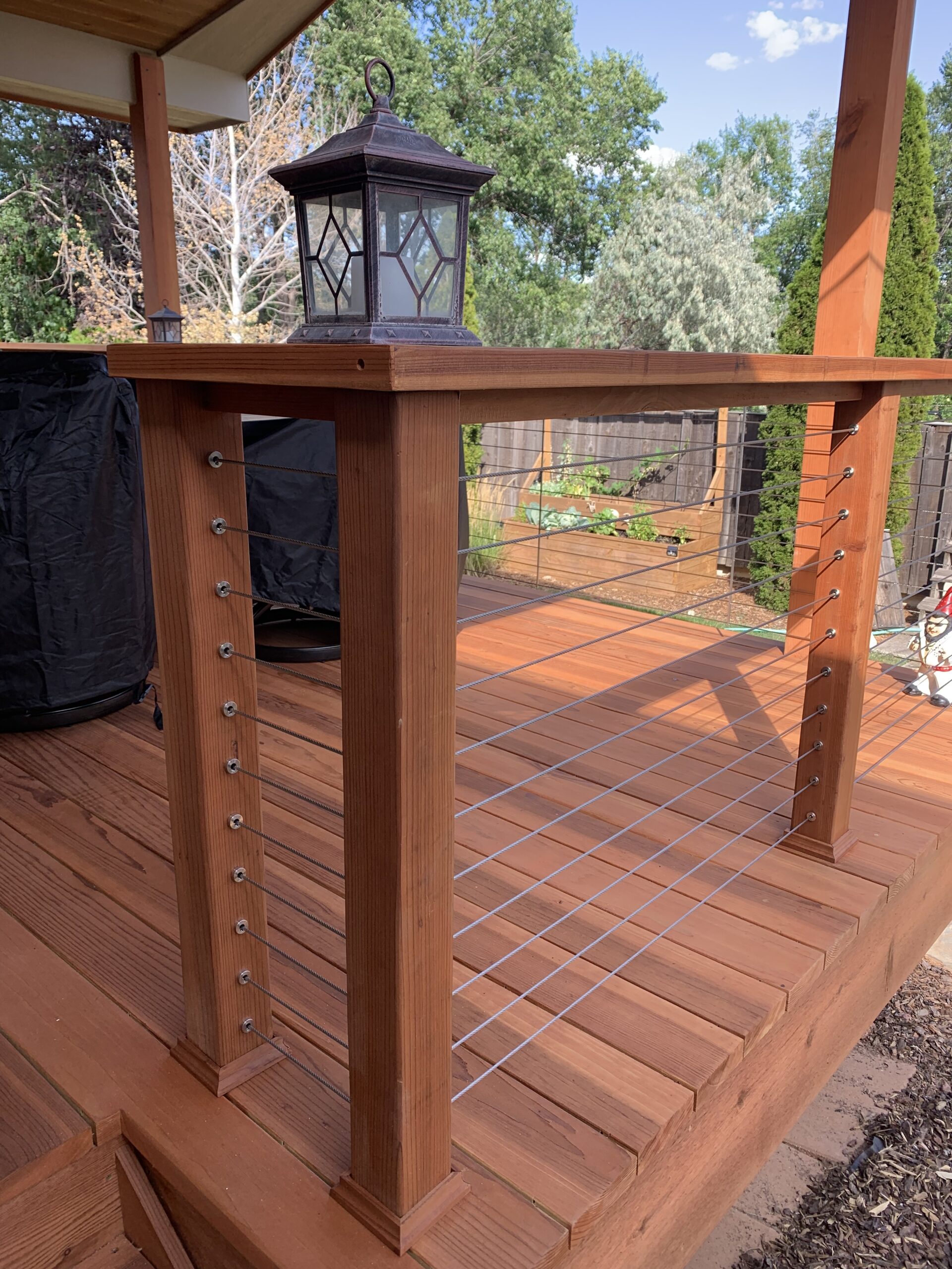 Custom designed railing with wood posts and drink cap and horizontal stainless-steel cables.
