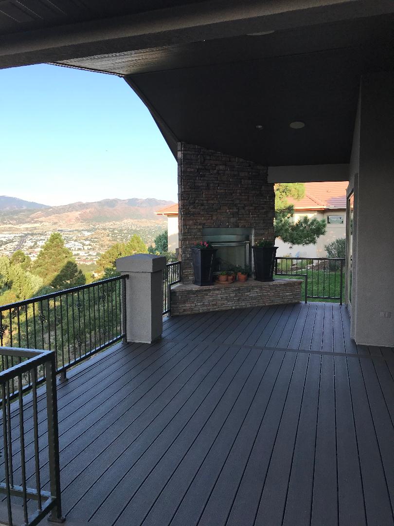 Composite deck with Deckorators Ironwood, powder coated metal railing, and stone fireplace.