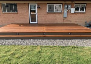 After picture - DBS built this gorgeous Camaru hardwood deck with wraparound step, in place of the concrete patio. We installed Genesis step lights on the stair riser for lighting at night.