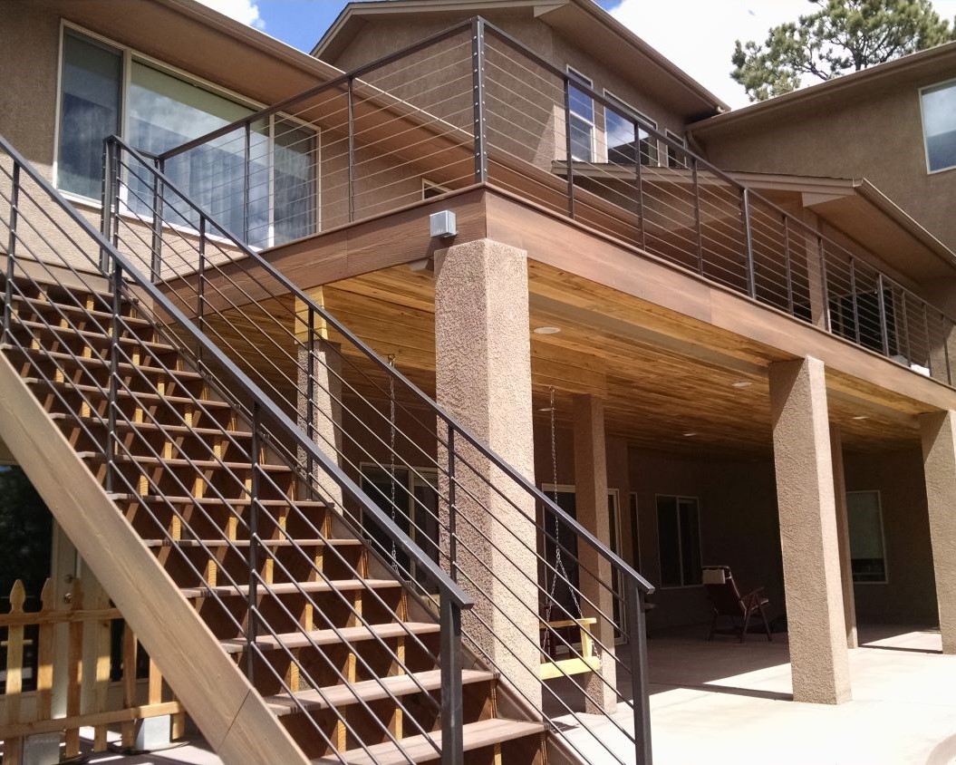 Custom, elevated composite deck with dry space below. Railing is metal with stainless steel horizontal cables.