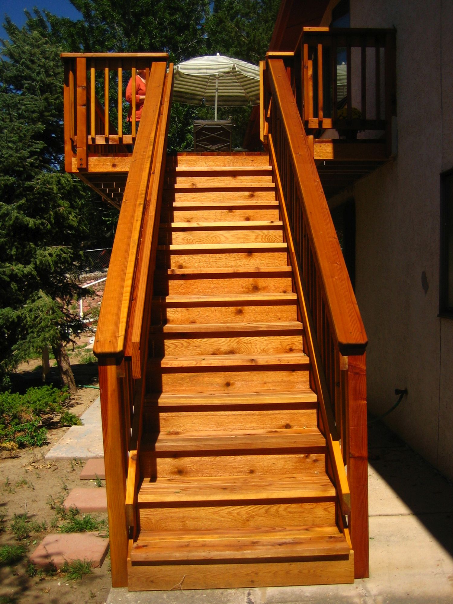 A redwood deck with picket fence railing. It has 3'-wide closed steps.