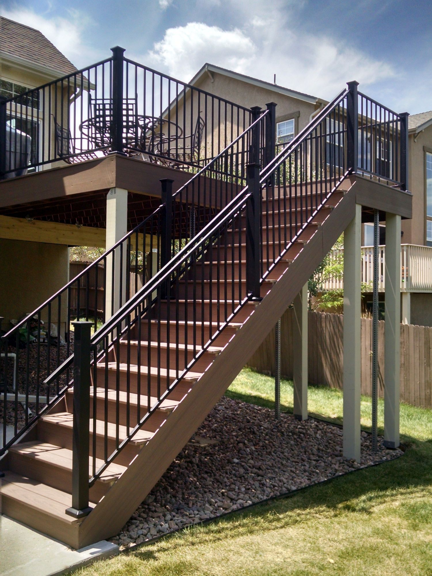 An elevated composite deck with a 4'-wide closed step staircase. The railing is a metal panel system with handrail for safety.