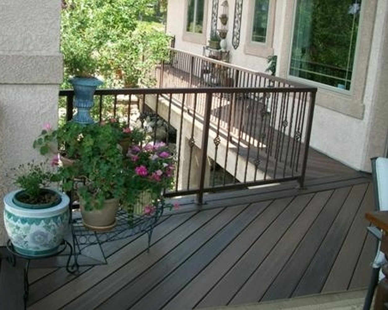 Composite deck with the boards laid at a 45-degree angle and a double picture frame border. An antique bronze metal railing with balusters featuring a basket design.