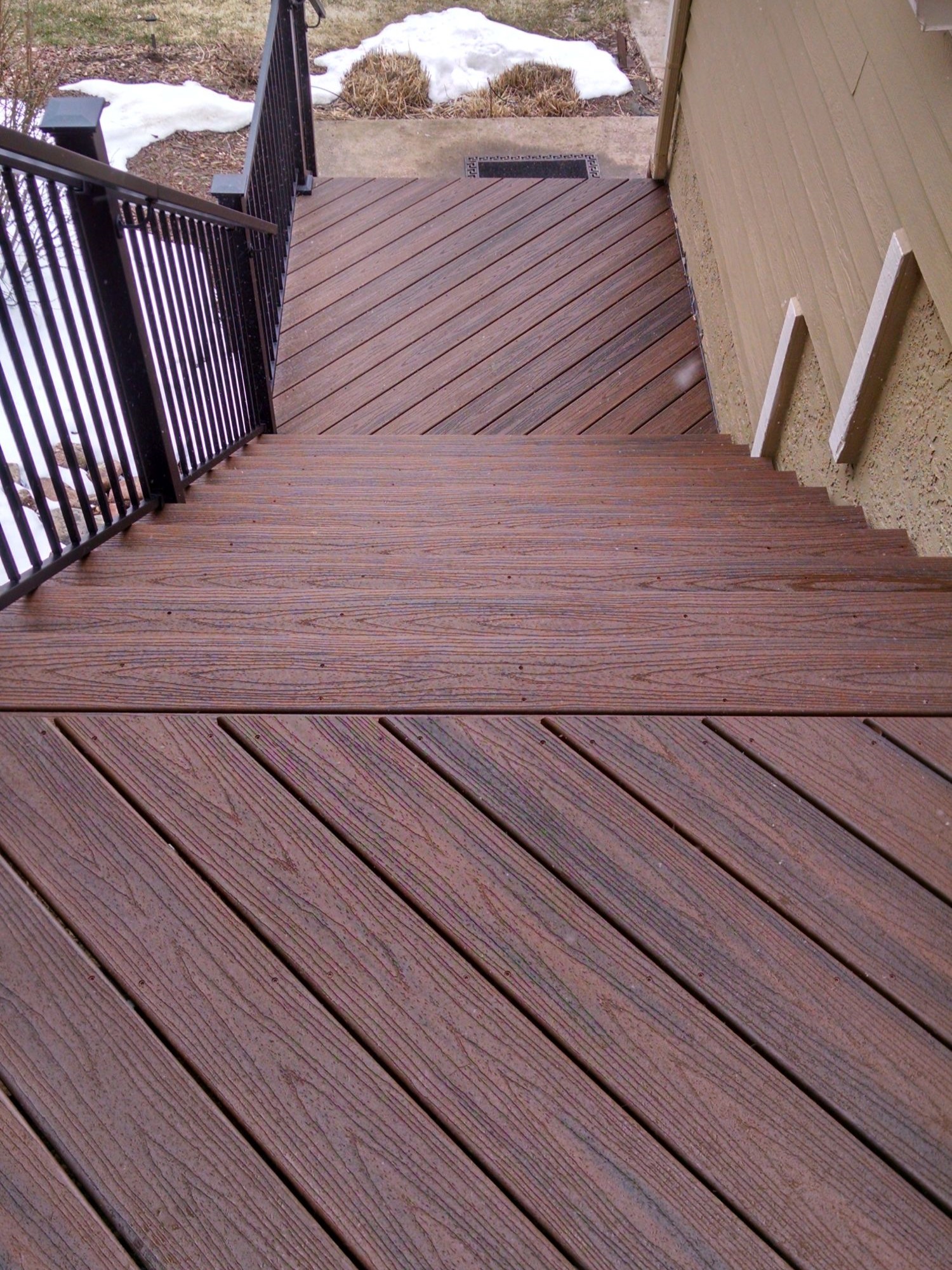Composite deck with multi-angled boards, metal railing, and 4'-wide deck stairs.