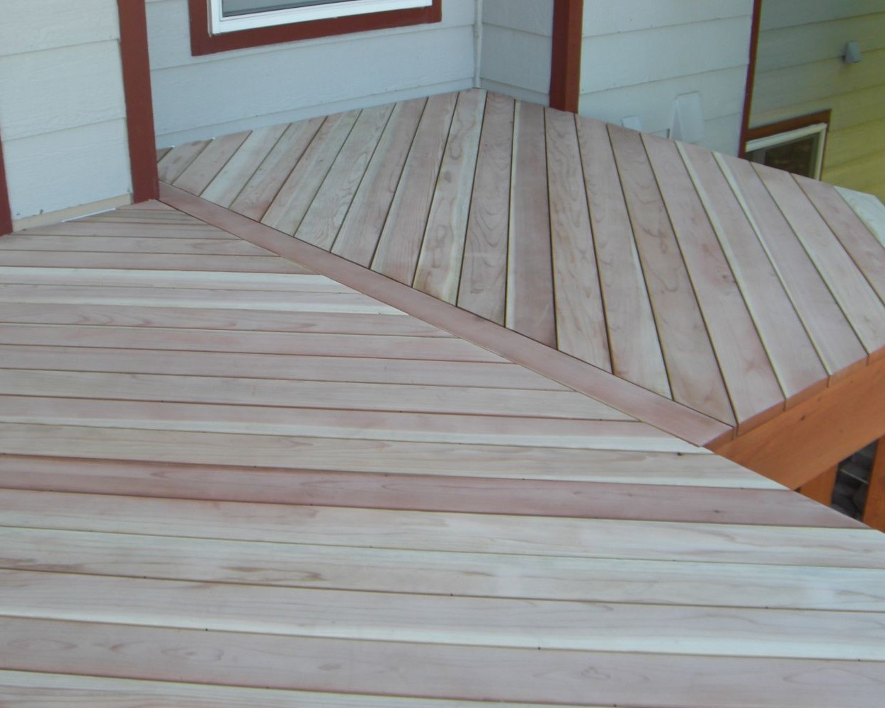 A B-grade Redwood deck in a herringbone pattern. The railing is not installed yet and the wood is unstained.