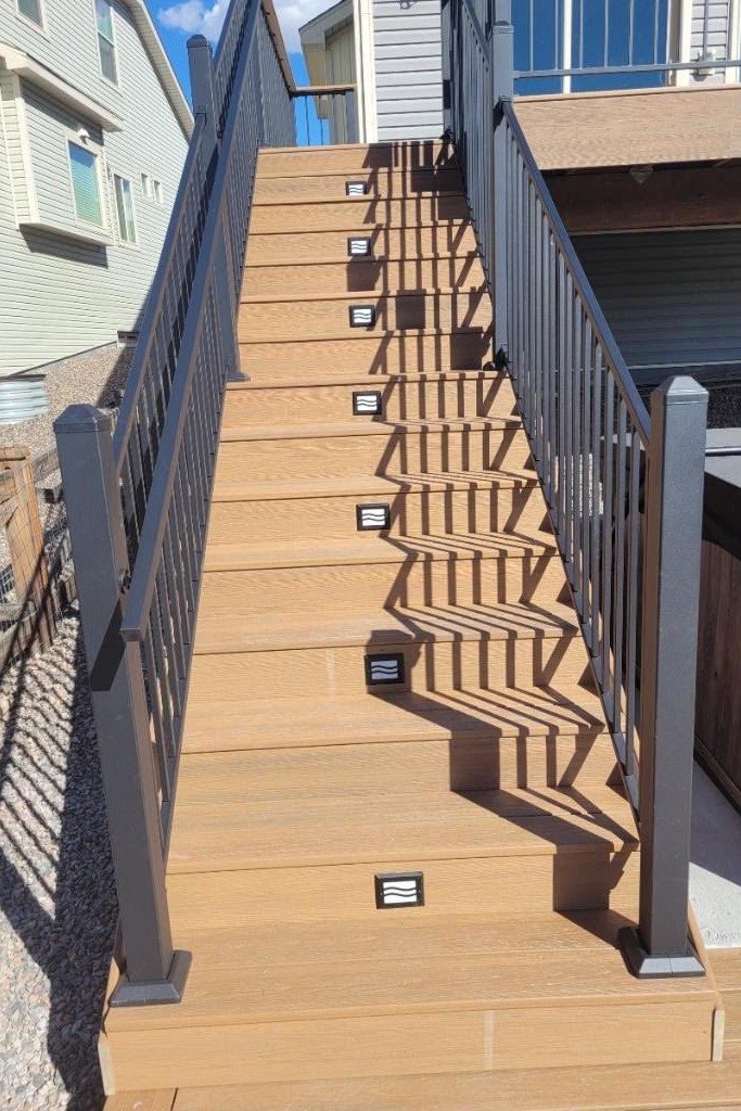 Two composite decks connected by a staircase with step lights installed for safety in the dark.
