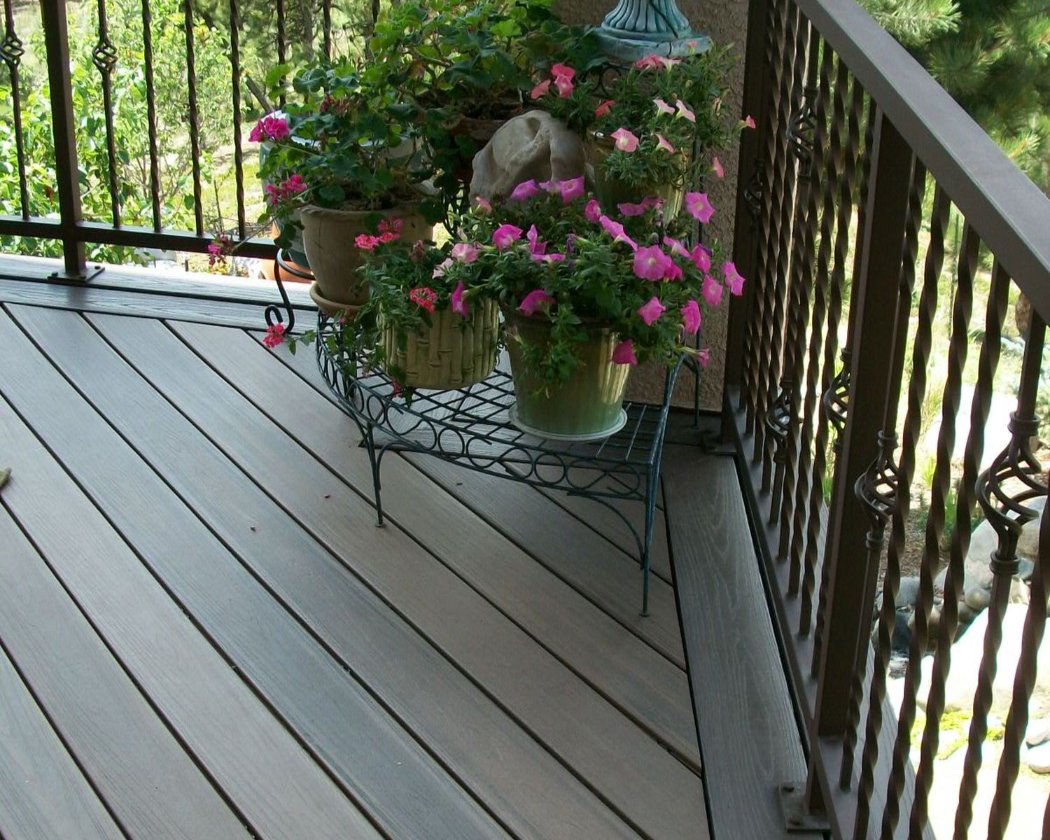 Composite deck with a double picture frame border. A metal panel railing with twisted, basket design balusters.