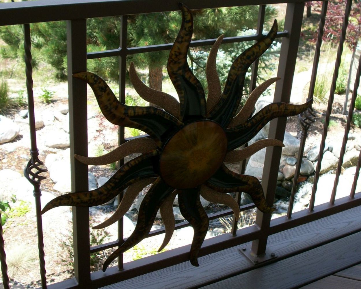 Metal panel railing system that was designed to showcase a piece of art (that looks like a sun) the homeowners wanted to showcase.