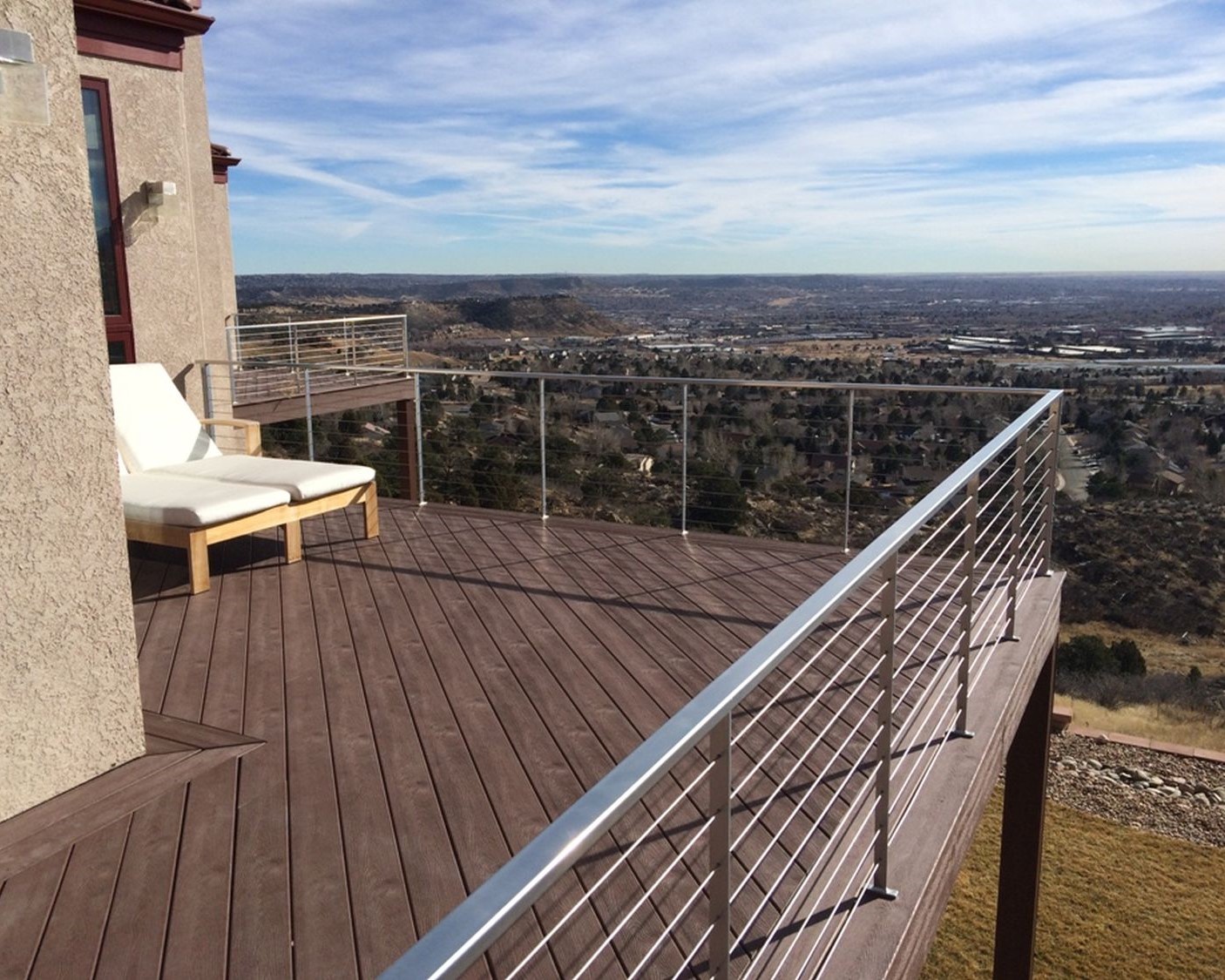 Composite deck with the boards laid at 45 degrees and a metal railing with stainless steel, horizontal cables.
