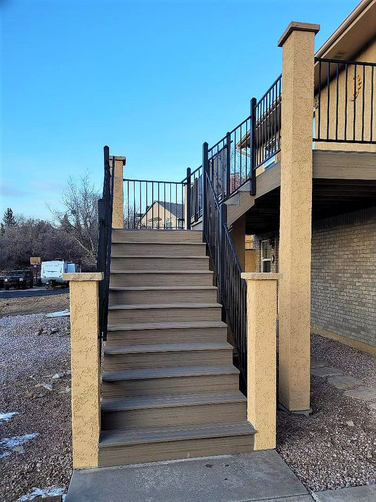 Closed, 5'-wide deck stairs with a metal panel railing and stucco columns.