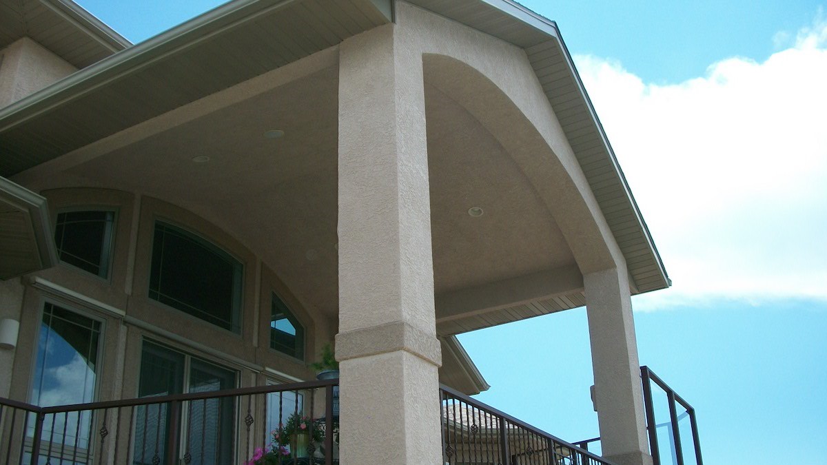 Custom built gabled deck cover that has a stucco, vaulted ceiling and recessed lighting.
