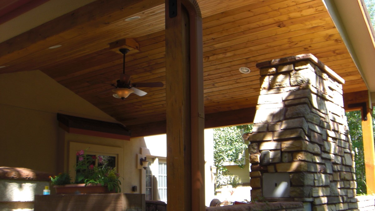 Deck that features a gabled tongue and groove ceiling and a custom stone, wood-burning fireplace
