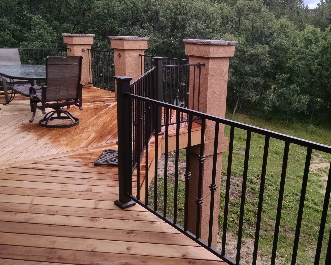 Heart redwood deck with a herringbone design, stucco columns, and metal panel railing.