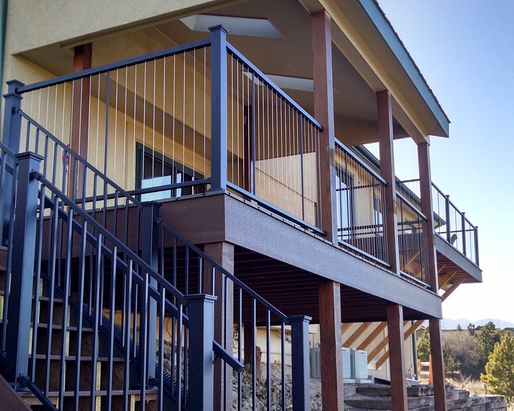 A covered composite deck with a metal railing featuring vertical steel cables.