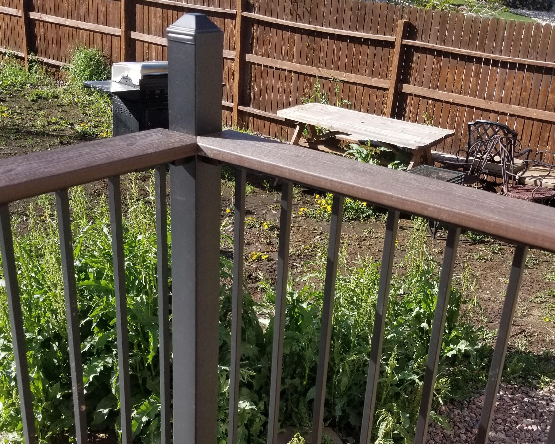 Composite deck with a Fortress Fe26 panel railing system that has raised posts, post caps, and a composite drink cap installed lower than the post height.