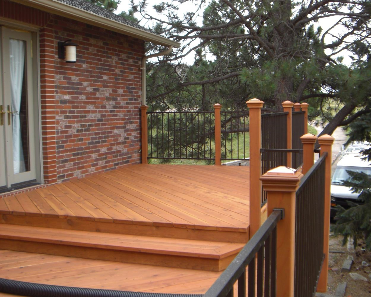 Multi-level Redwood deck with 45-degree angle boards. The railing is built with wood posts and metal panels between the posts.