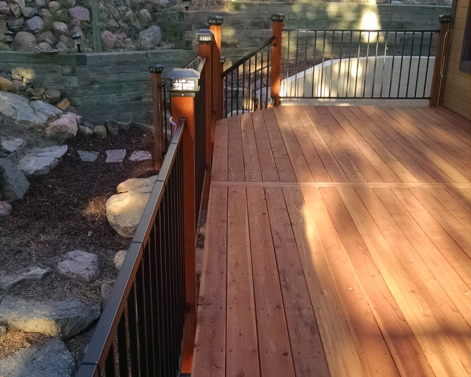 Redwood deck with 90-degree boards and a single dividing board. Metal panel railing installed between wood posts.
