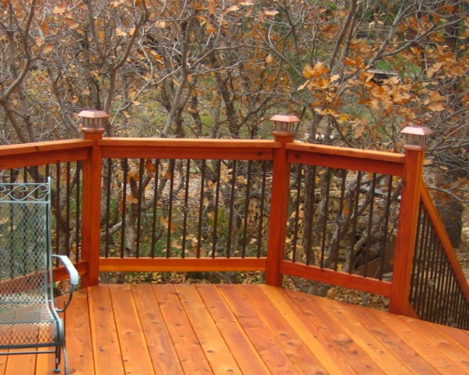 Redwood component deck railing with black metal balusters and copper post lights.