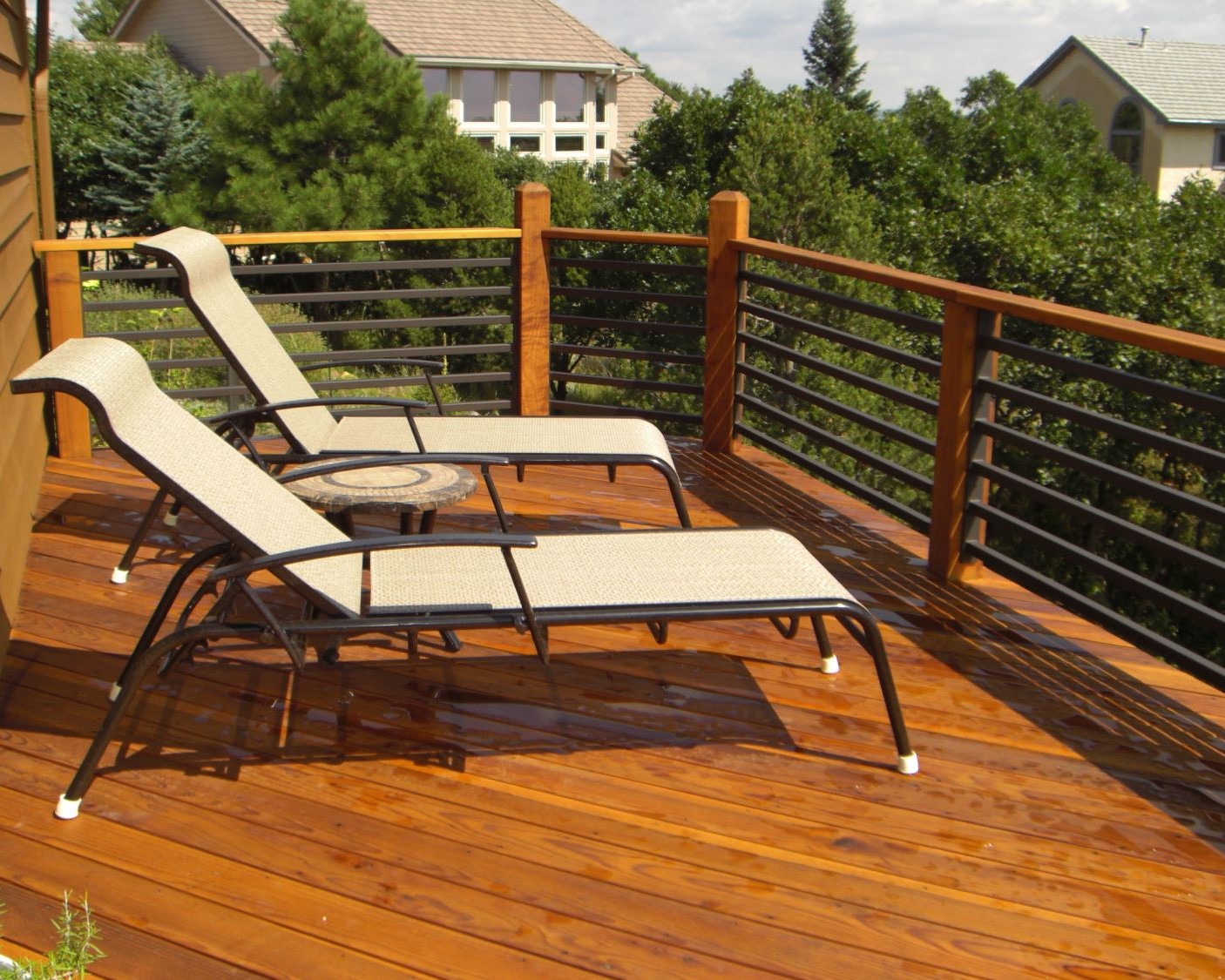 Redwood deck with a 45-degree design. The railing has wood posts and drink cap with square, black metal rails installed horizontally between the posts.