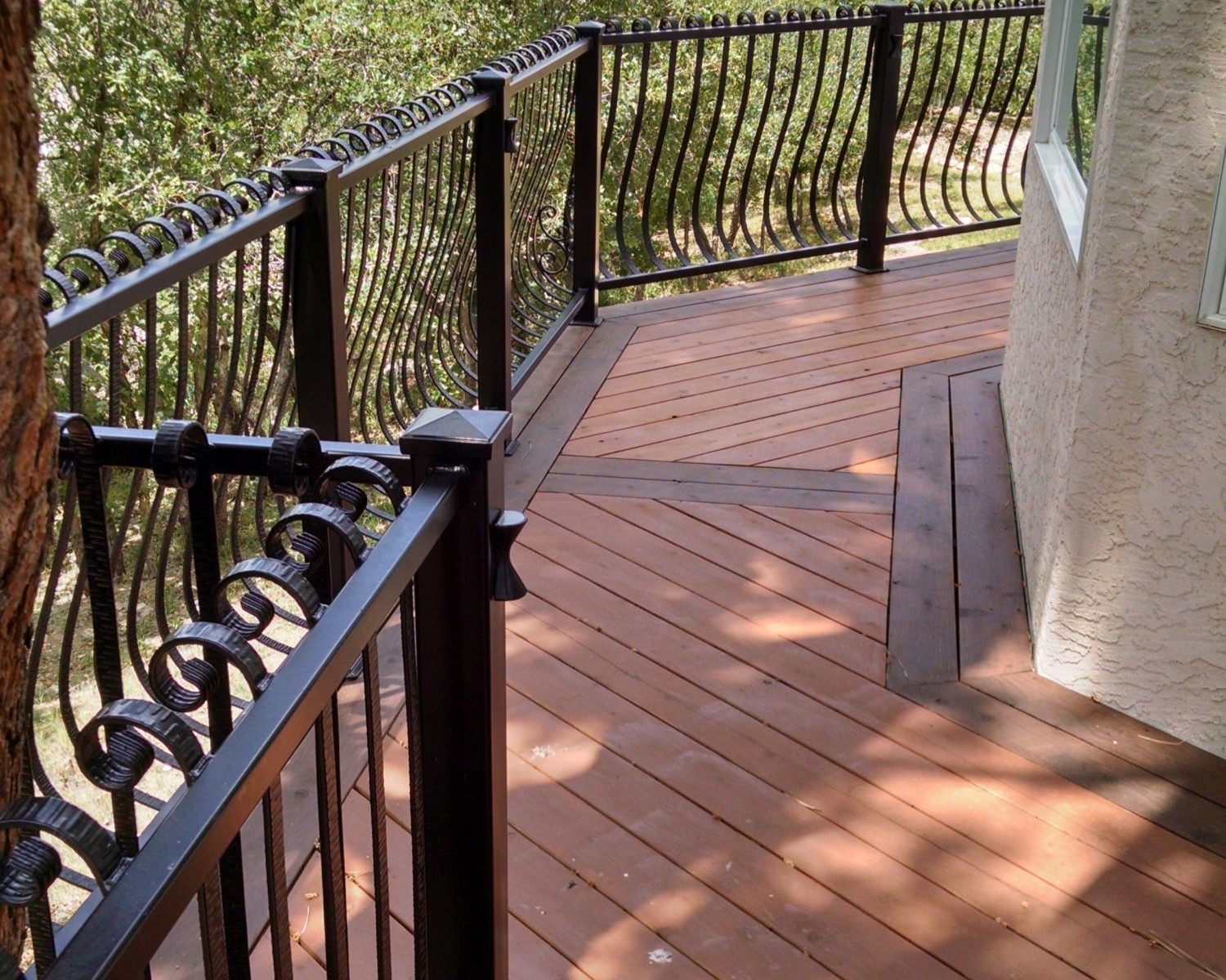 Heart Redwood deck laid at a 45-degree angle with a double picture frame border that is stained in a contrasting color. It also features a custom built wrought iron railing.