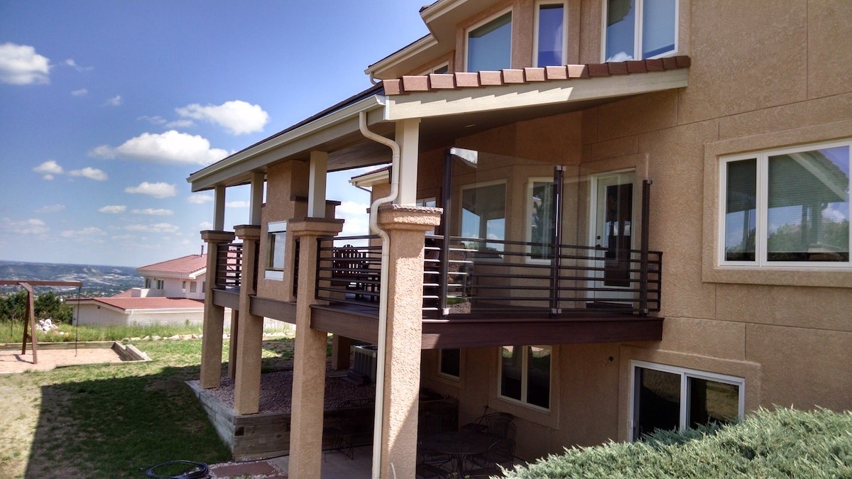 Custom composite deck with a closed-ceiling, shed roof deck cover, glass wind break, and double sided gas fireplace.