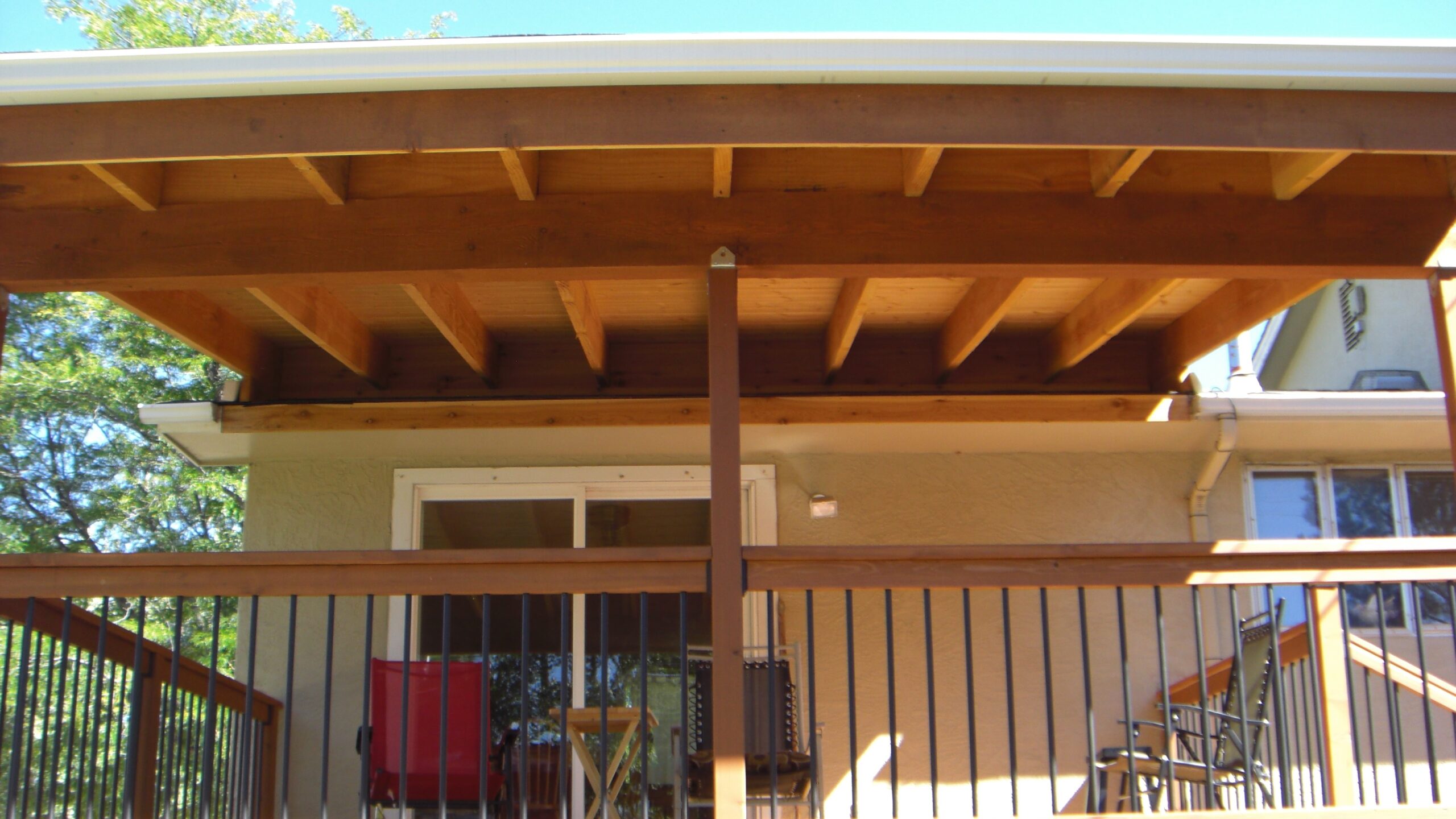 Custom deck with a shed roof deck cover that has an open ceiling.