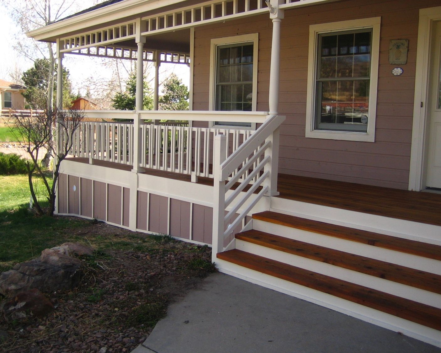 A front porch featuring a redwood snow fence railing with a unique rectangular design element.