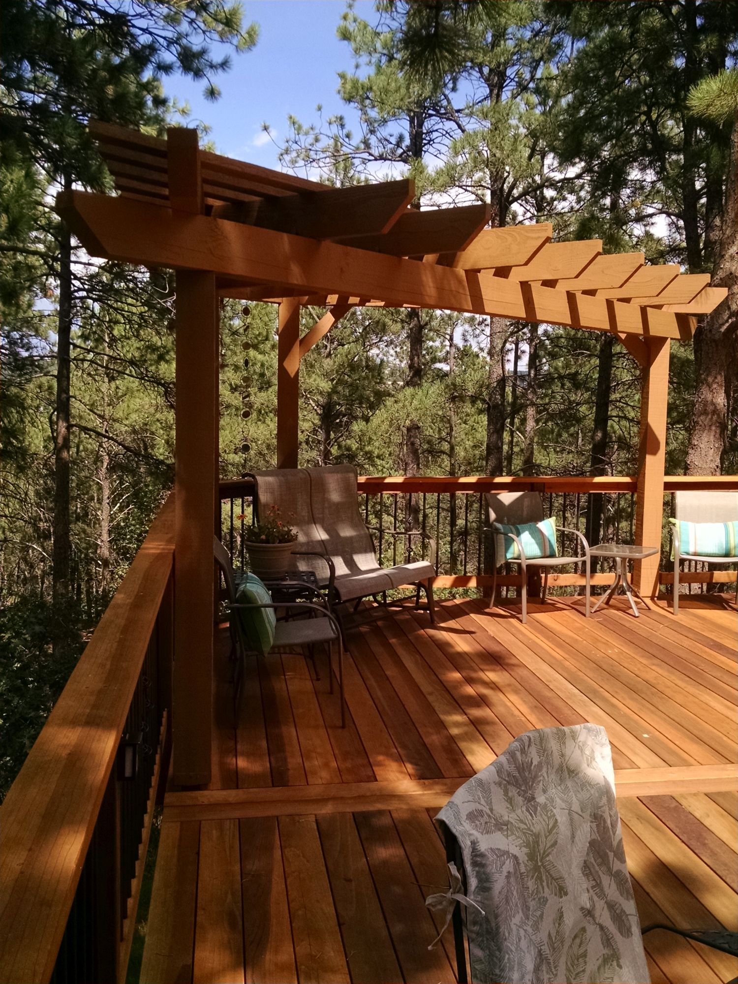 B-grade Redwood deck with a tri-corner pergola creates a gorgeous seating area in the forest.