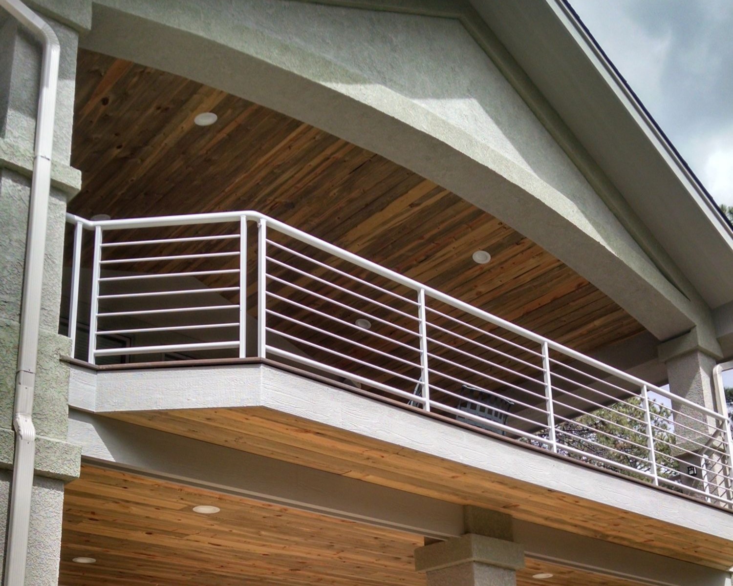 Custom deck with gabled deck cover that features a white metal railing with horizontal balusters.