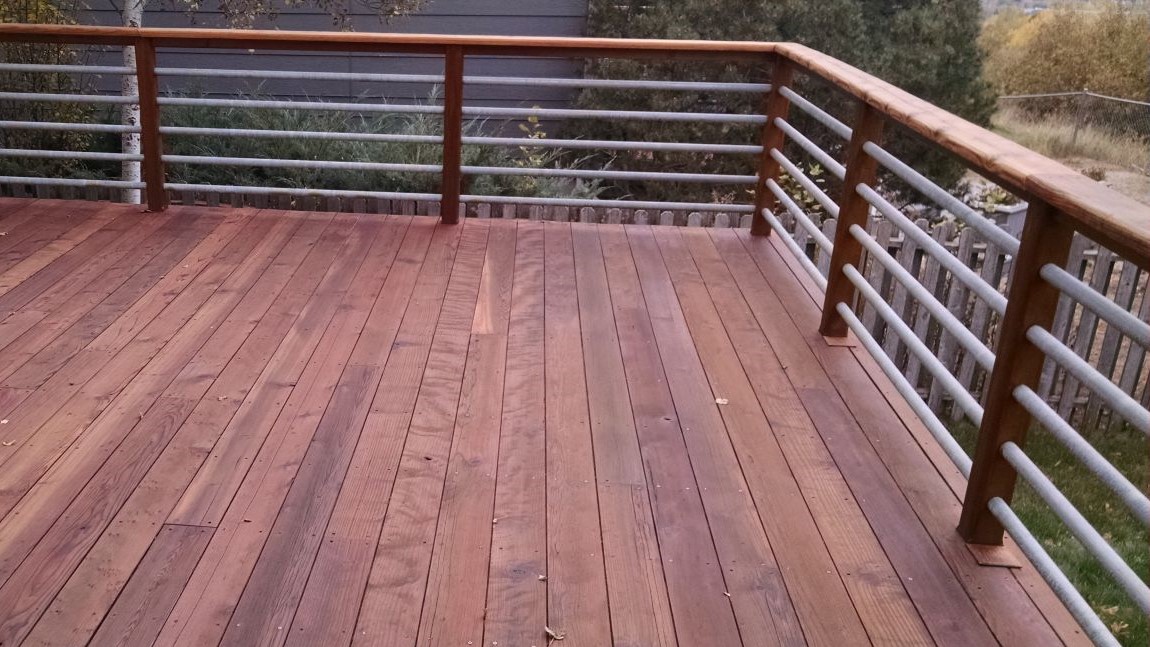 Redwood deck with a railing built from wood components and round, metal, horizontal balusters.