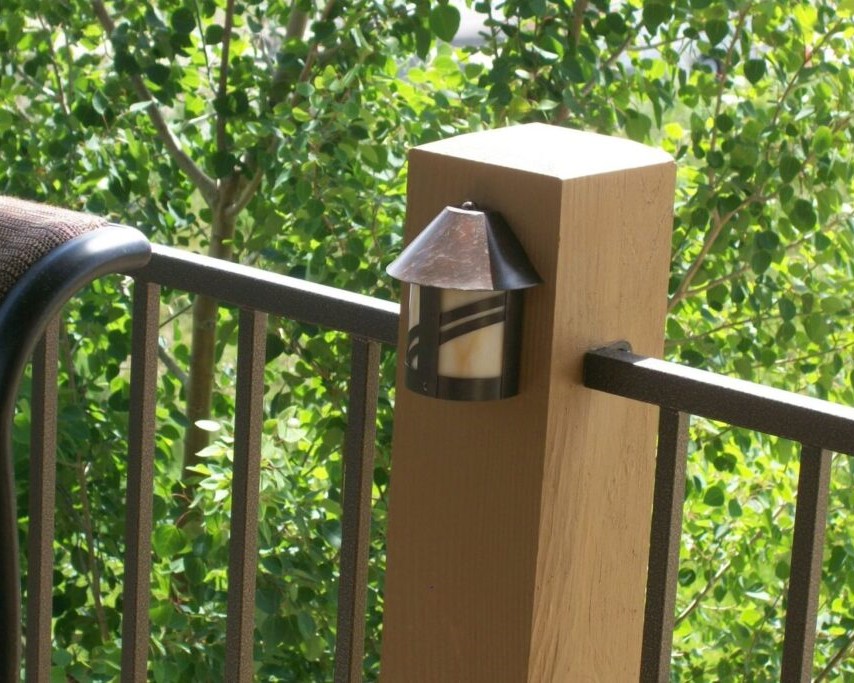 Deck railing with wood post and a railing light installed for evening lighting.