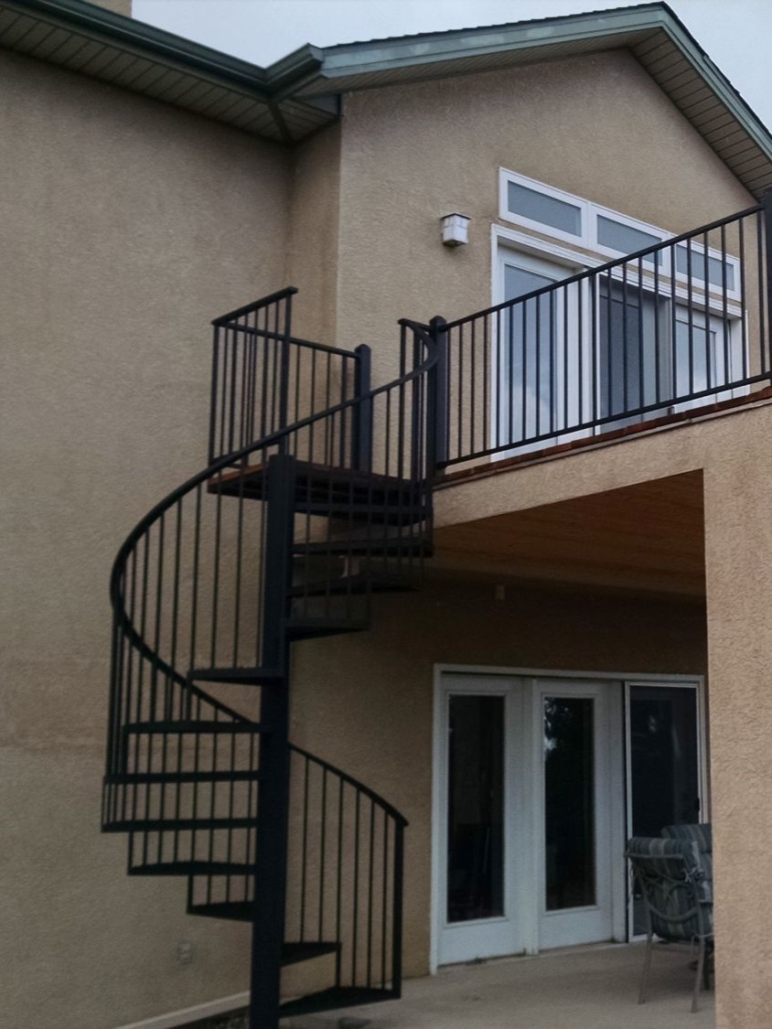 A wrought iron spiral staircase for a deck with metal step treads