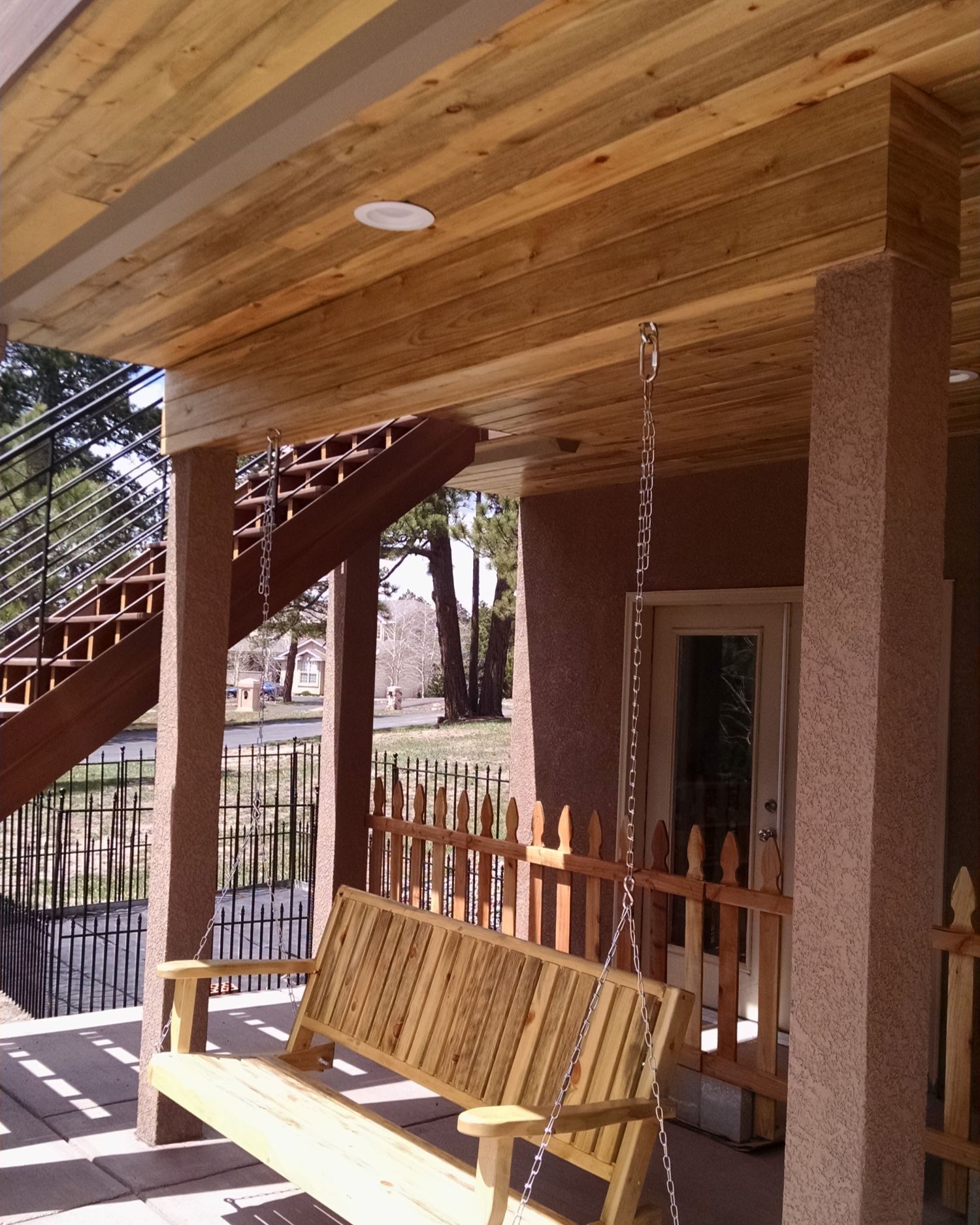 Under-deck drainage system with a Beetle Kill Pine tongue and groove ceiling and recessed lights. We also installed a wood swing for the owners to enjoy.