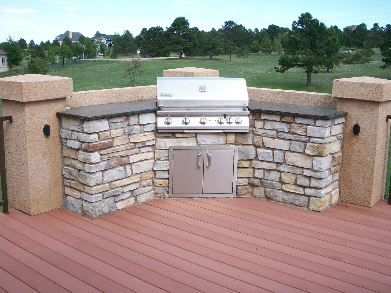 Redwood deck with a grilling/cooking area in one corner. Built with stone and granite countertops