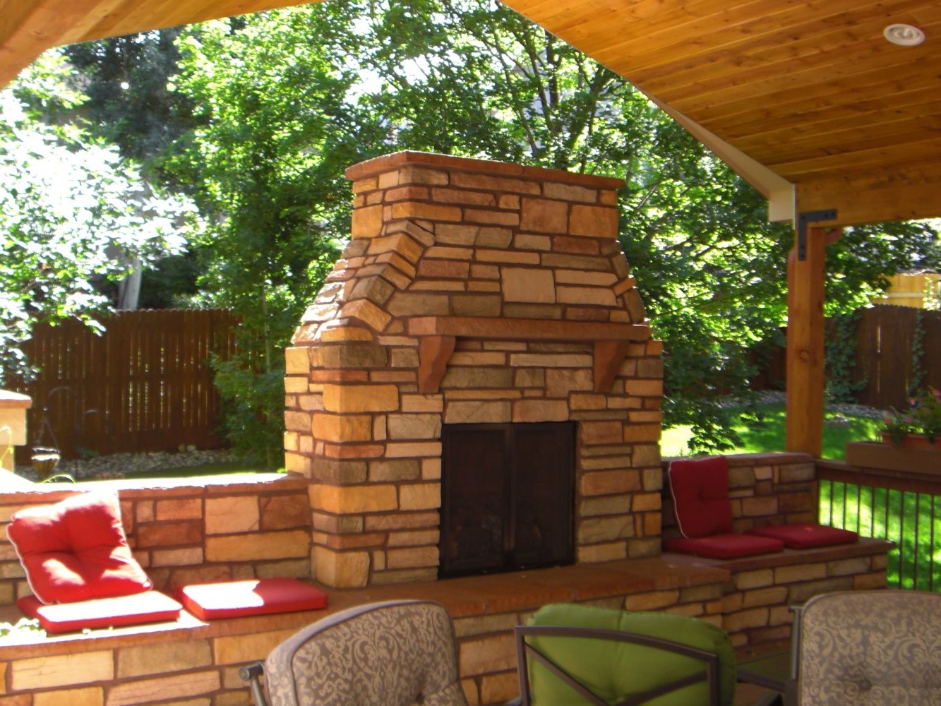 Wood-burning, stone fireplace on a covered deck.