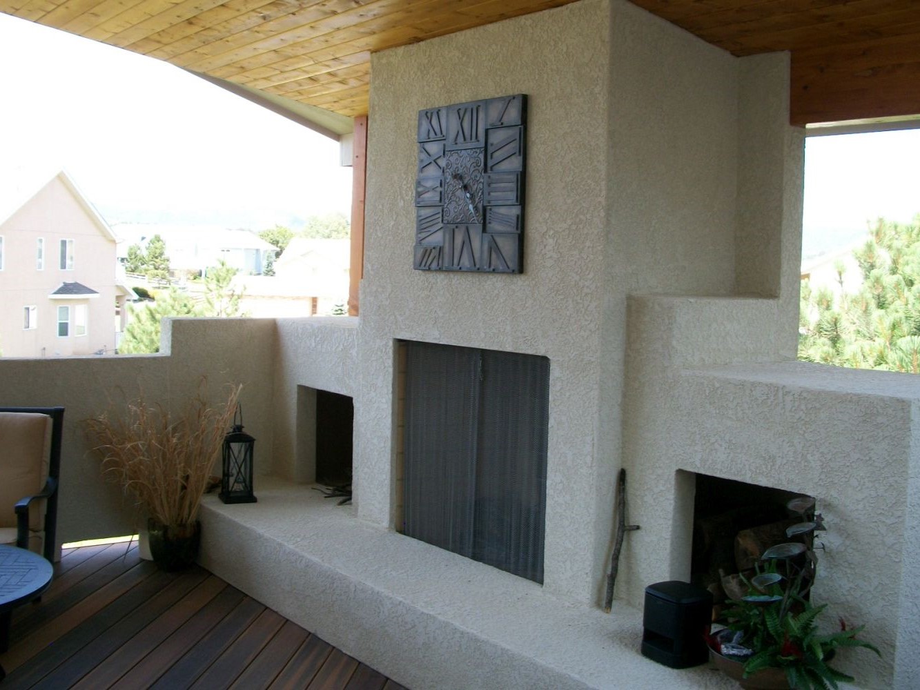 Covered, composite deck with a custom-built wood-burning stucco fireplace.