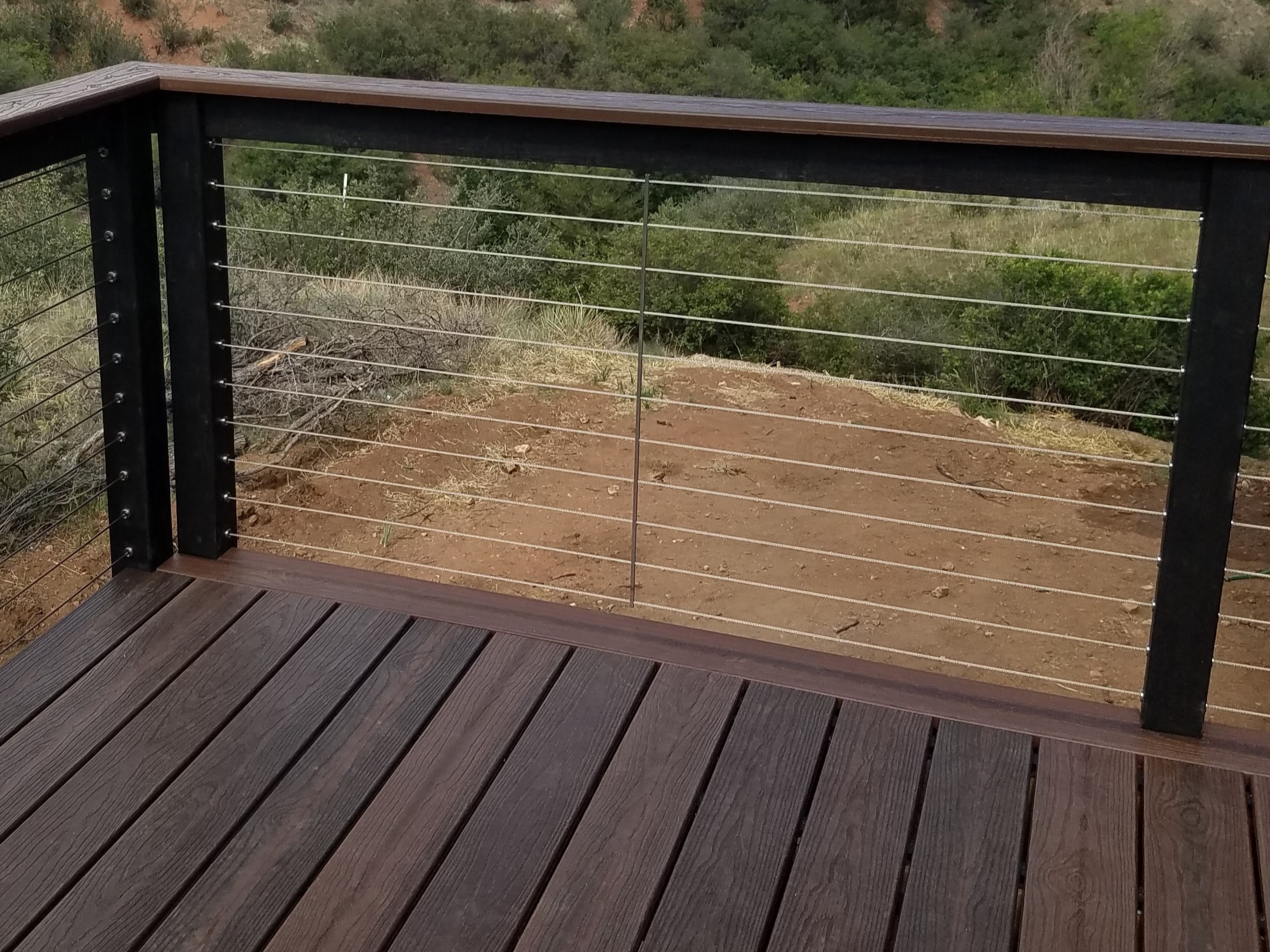 Composite deck with end boards. The railing features composite components and vertical steel cables.