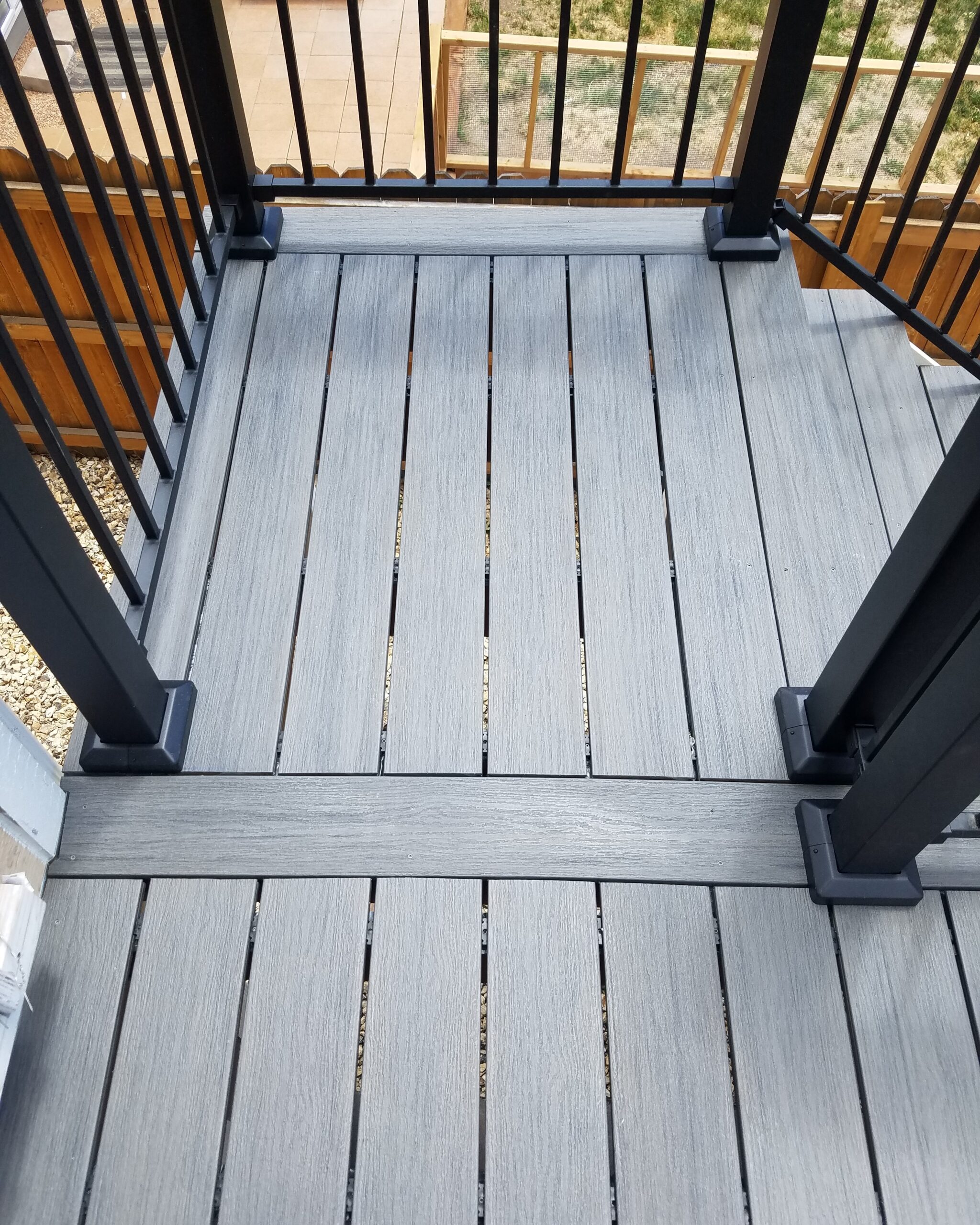 90-degree composite deck with end boards and a Fortress Fe26 metal panel railing in Black.