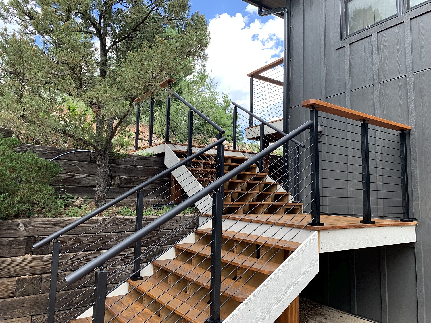 Deck stairs with a landing done in Cumaru hardwood. The railing is a custom ViewRail Onyx system in matte black