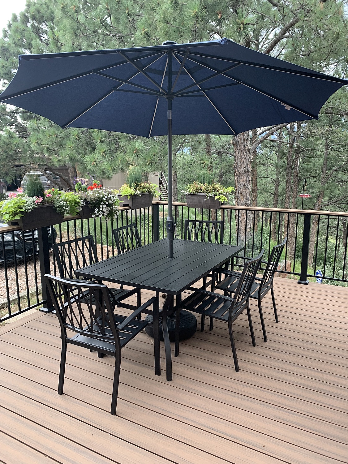 Composite deck with a black metal railing. The owners have added flower boxes along the railing and a dining area for entertaining.