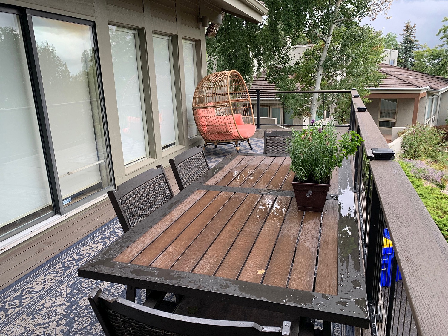 Homeowners have created a beautiful, outdoor living space on their new composite deck with a dining table, chairs, and outdoor rug.