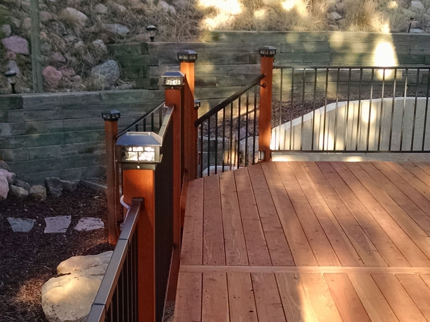 Deck railing with wood posts, metal panels, and lighted post caps