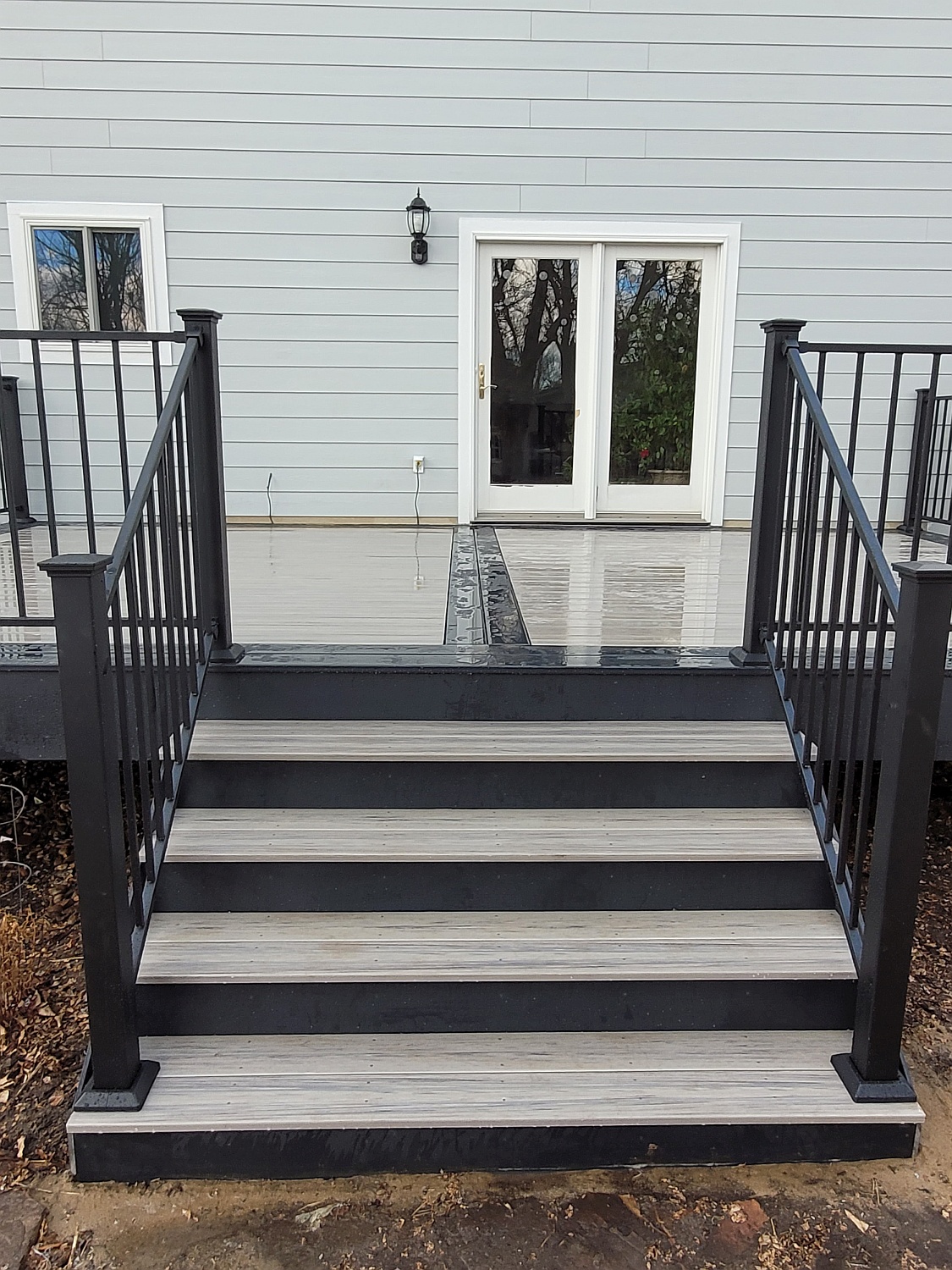 A set up of deck stairs that have a light gray tread with a dark slate riser to create a beautiful contrast.