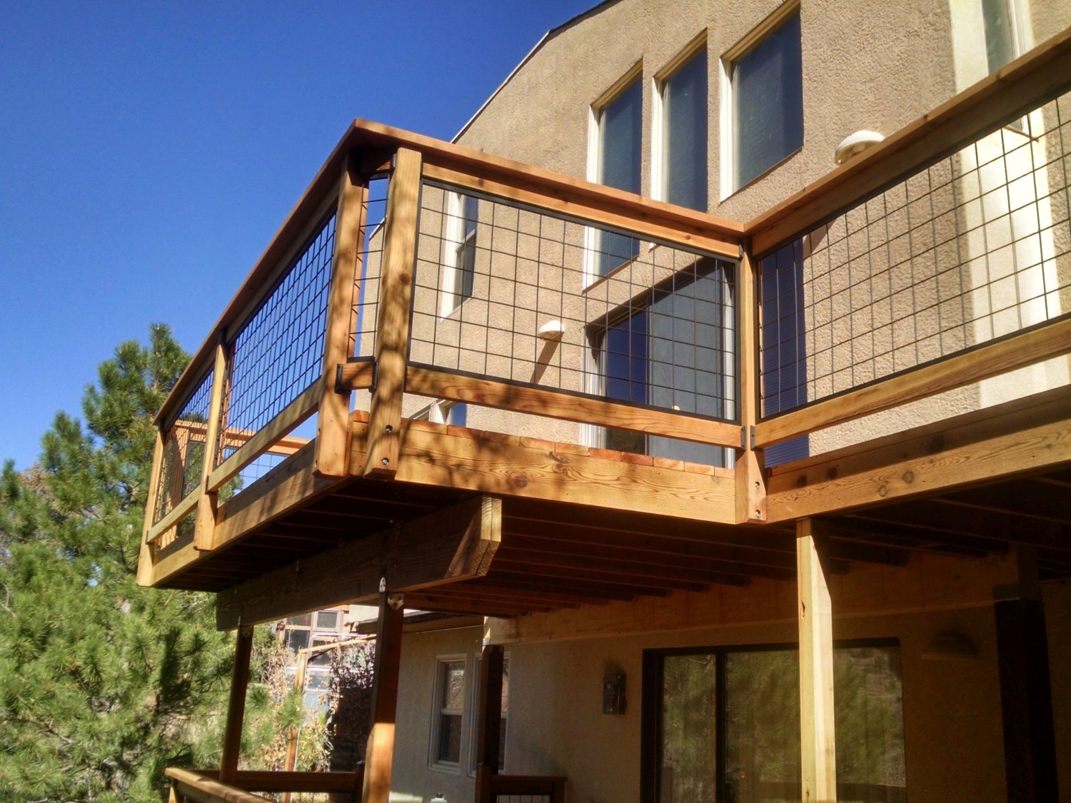 Elevated redwood deck that has a wood railing with Wild Hog metal grid panels installed.