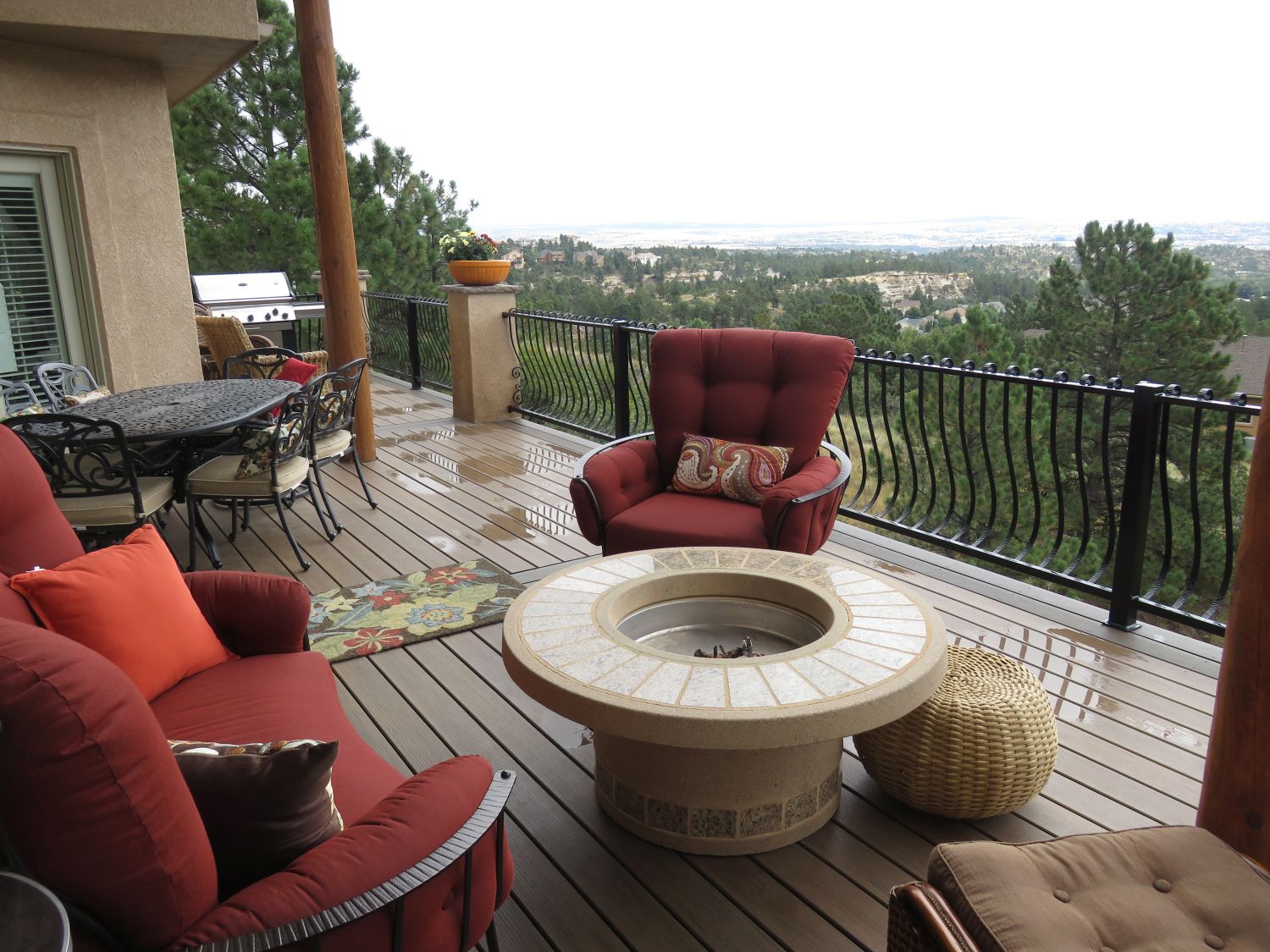 Elevated deck with cushy outdoor chairs surrounding a firepit.