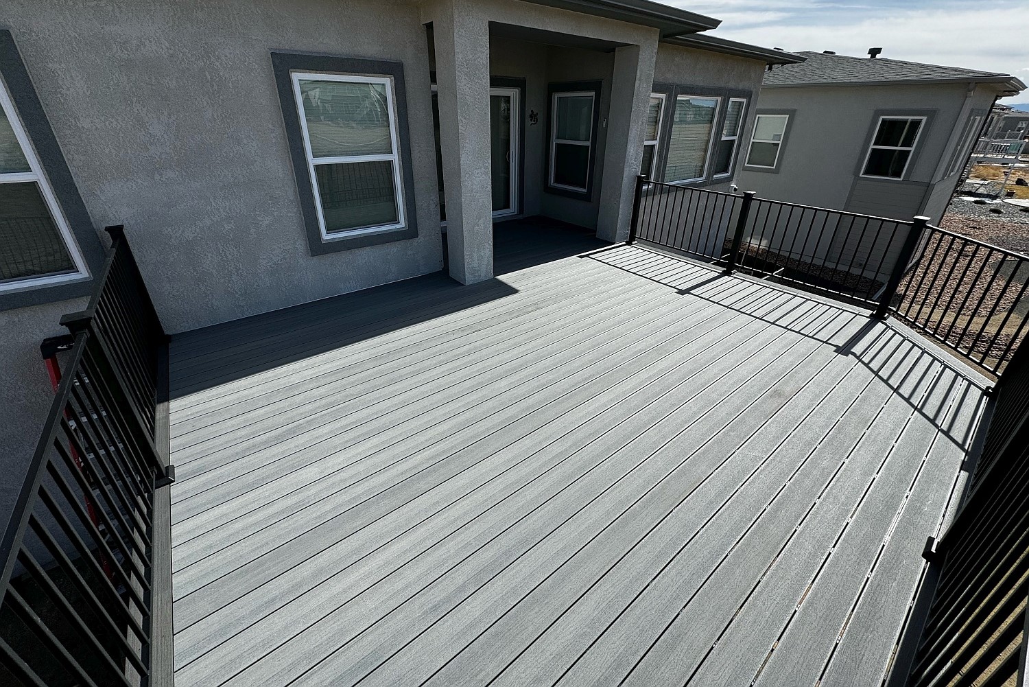 Beautiful composite deck in light grey color with a black metal deck railing.