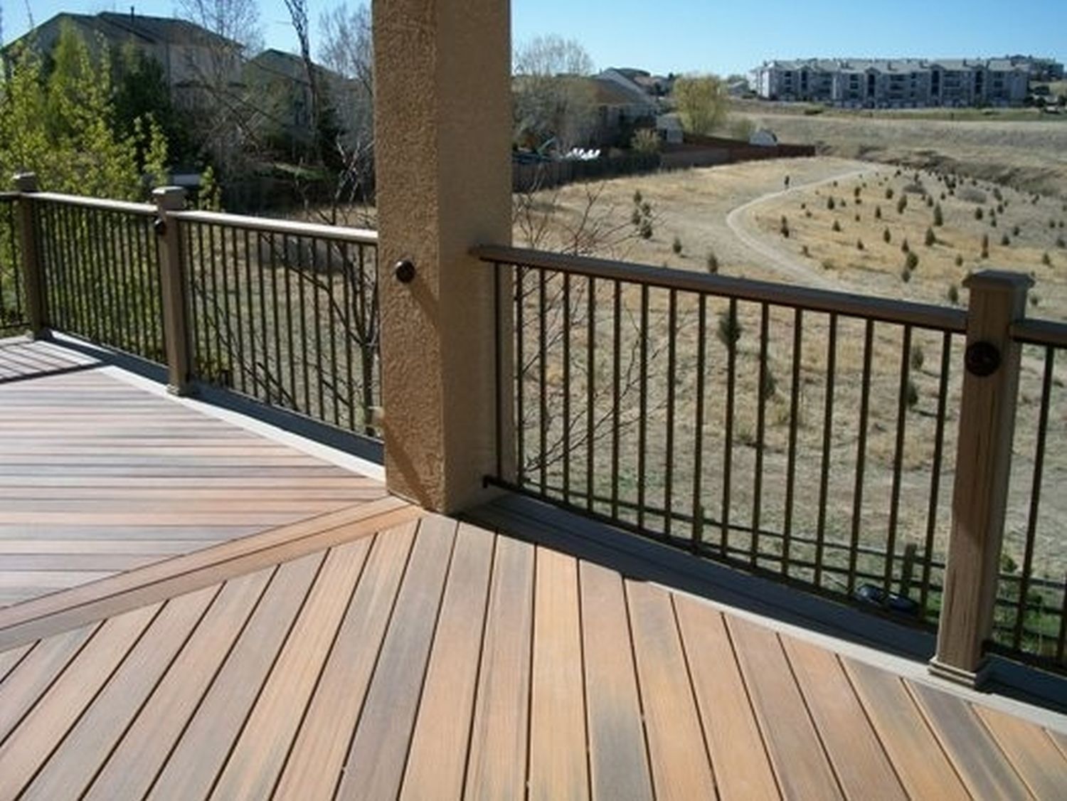 Composite deck with herringbone board design, a black metal railing, and deck cover.