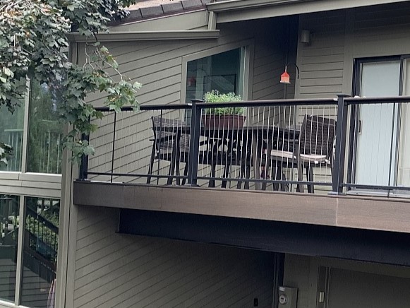 A composite deck with a metal railing that has vertical stainless steel cables.